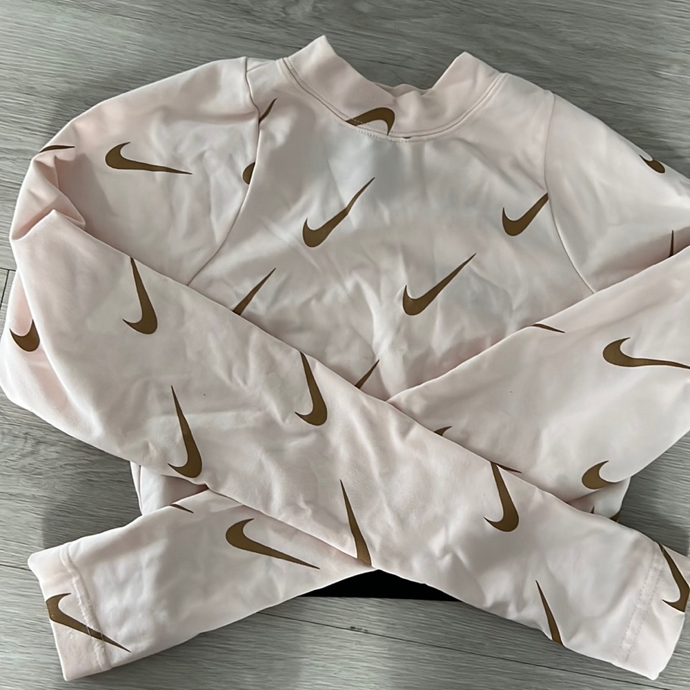Tue shirt is a long sleeved from Nike with the color pink and gold .